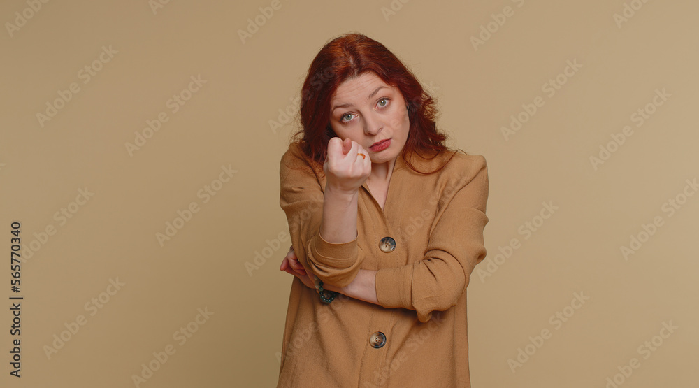 Angry aggressive redhead woman showing fig negative gesture, you dont get it anyway. Rapacious, avaricious, acquisitive. Body language. Refusal fig sign. Greedy avaricious girl on beige background