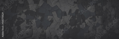 Dark wide panoramic background. Peeling paint on a concrete wall. Faded dark texture of old cracked flaking paint. Weathered rough painted surface with patterns of cracks. Shaded background for design