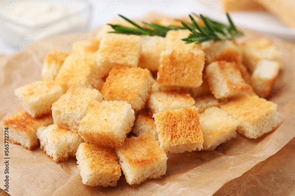 Delicious crispy croutons with rosemary on wooden board, closeup Delicious crispy croutons with rosemary on wooden board, closeup