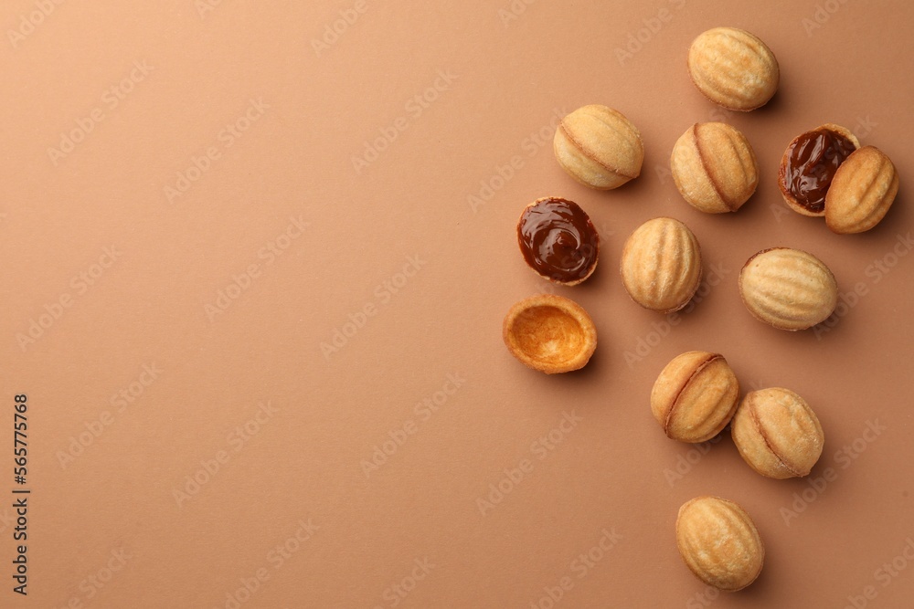 Homemade walnut shaped cookies with boiled condensed milk on pale brown background, flat lay. Space for text