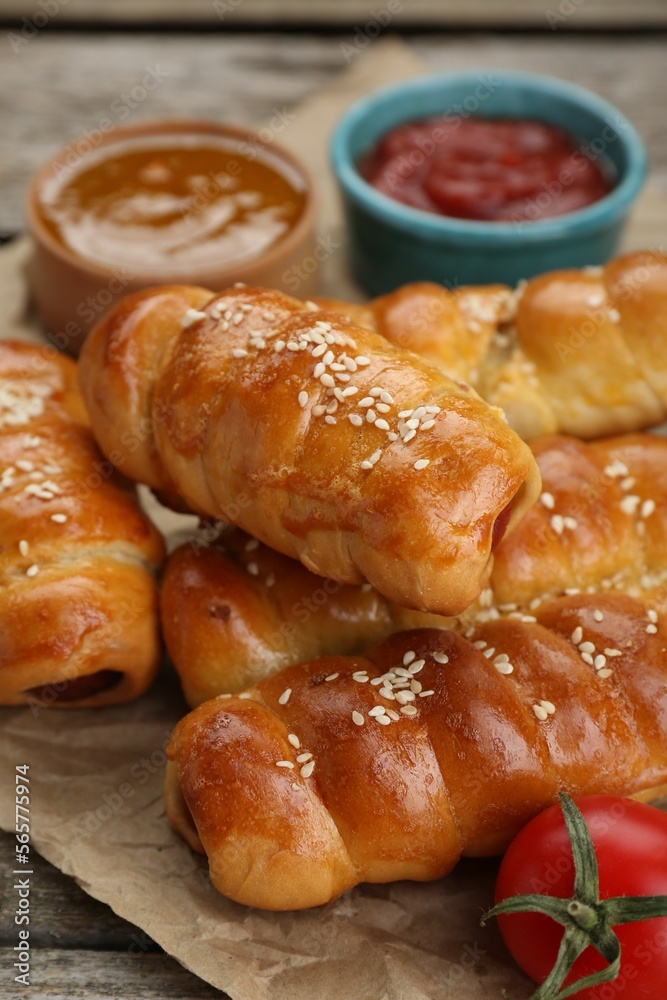 Delicious sausage rolls and ingredients on wooden table, closeup Delicious sausage rolls and ingredients on wooden table, closeup