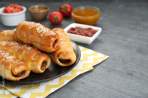 Delicious sausage rolls and ingredients on grey table, closeup. Space for text