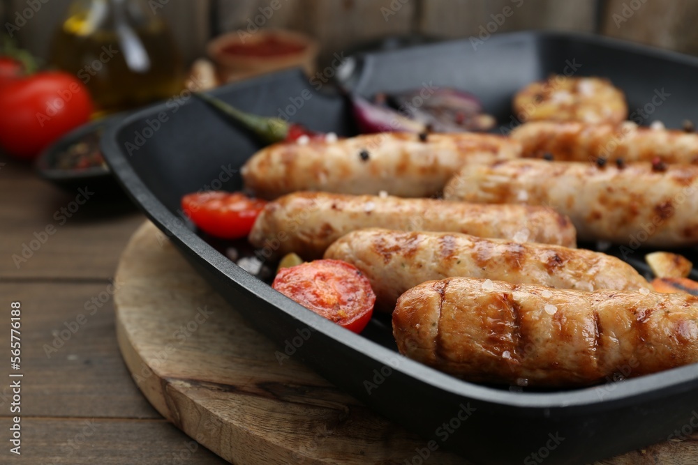 Tasty grilled sausages with vegetables on wooden table, closeup. Space for text