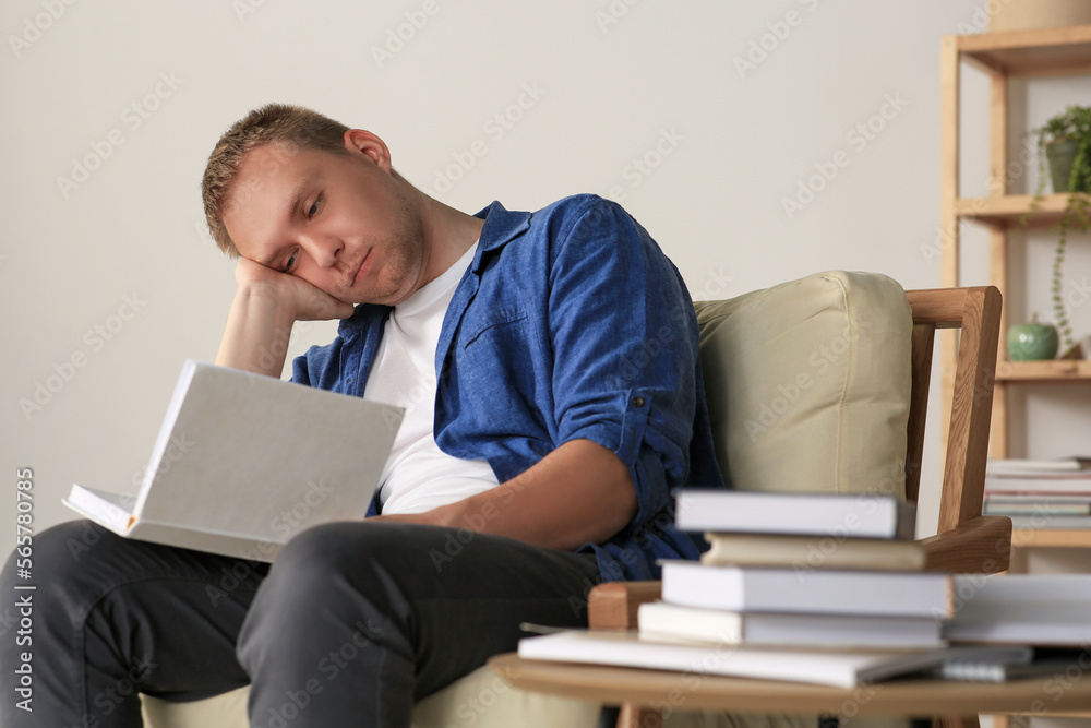 Tired man studying in armchair at home Tired man studying in armchair at home