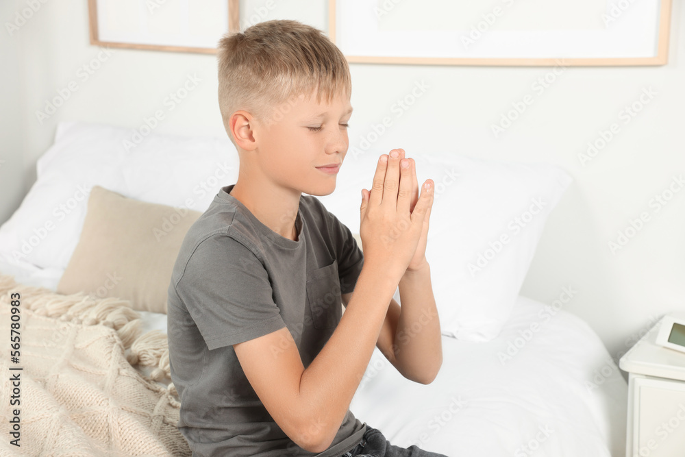 Boy with clasped hands praying on bed at home Boy with clasped hands praying on bed at home