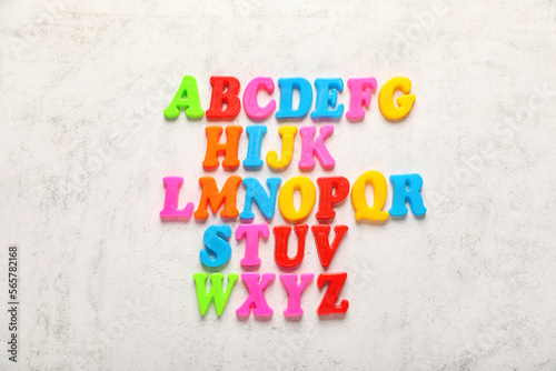 Colorful magnetic letters on white textured background, flat lay. Alphabetical order