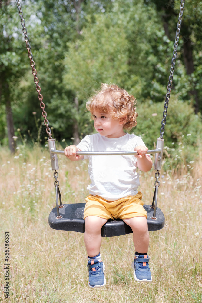 Blond preschooler swings in the field. Concept of childhood. Blond preschooler swings in the field. Concept of childhood.