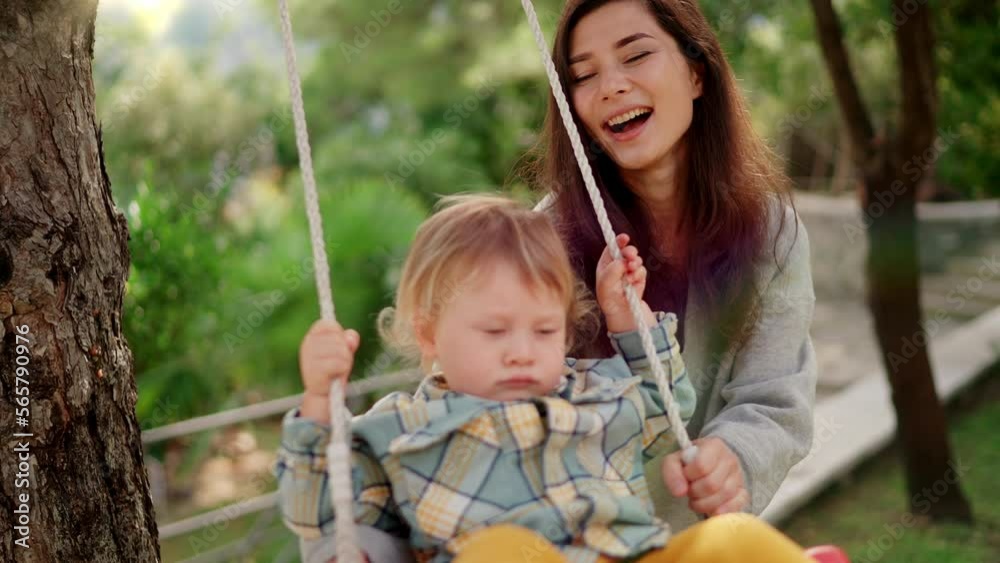 Happy mother play with little son in back yard on swing Happy mother play with little son in back yard on swing