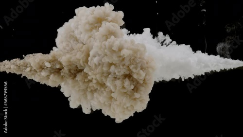 Macro shot of brown and white inks are being injected in water from two different sides mixing into beige one on black background | Abstract skin care cosmetics ingredients mixing concept