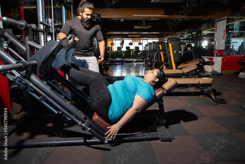 Young overweight indian woman workout in gym with trainer to lose weight and burn belly fat exercise. fitness and health care