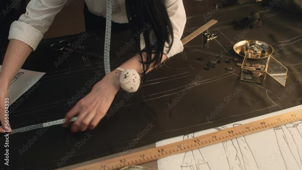 Male and female tailors work on sketch pattern on the fabric of future ...