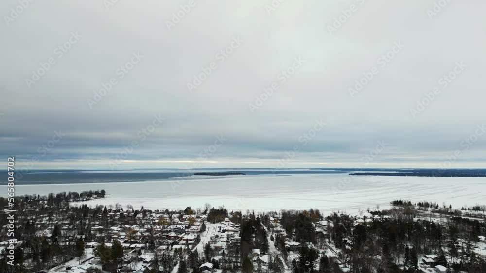 Winter time Lake Simcoe drone view frozen lake houses and treetops cloudy day Winter time Lake Simcoe drone view frozen lake houses and treetops cloudy day