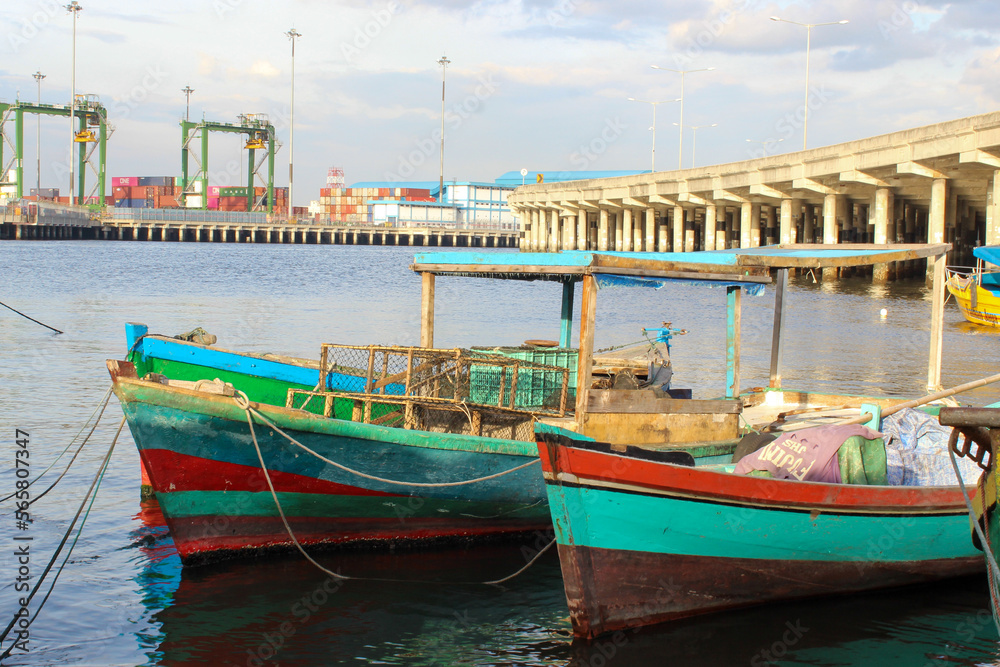 portrait of traditional fishing boats that lean on the dock beside the largest container port in Indonesia