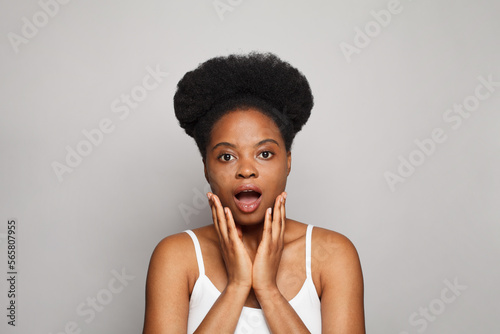 Screaming young brunette woman standing on grey studio wall background