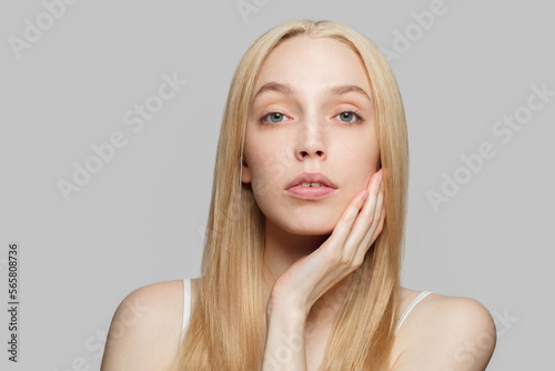 Beautiful woman with long blonde hair in white top isolated on grey. Beauty  cosmetics  skincare  glamour