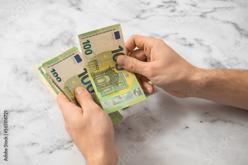 A man counts euro money with his hands on a light background photo