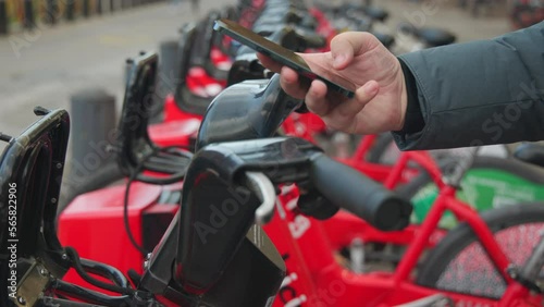 Wallpaper Mural Close-up shot of unrecognized tourist using bicycle rental dock. Detailed view of a male hand holding a smartphone to rent a bike from a station. High quality 4k footage Torontodigital.ca