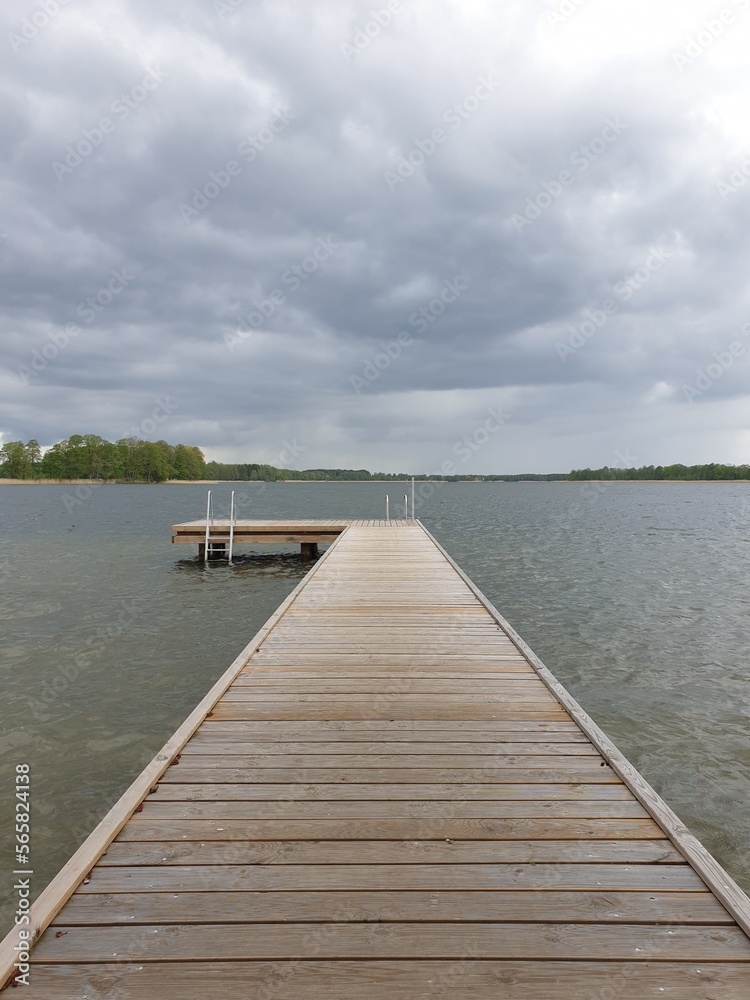 Wooden walkway on the river with cloudy sky in the background