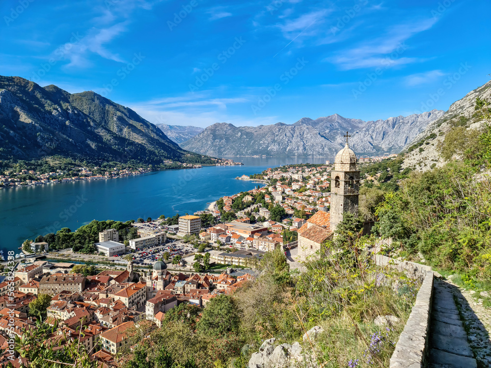 Panoramic view from Kotor city walls on Church of Our Lady of Remedy and Kotor bay in sunny summer, Adriatic Mediterranean Sea, Montenegro, Balkan Peninsula, Europe. Fjord winding along coastal towns