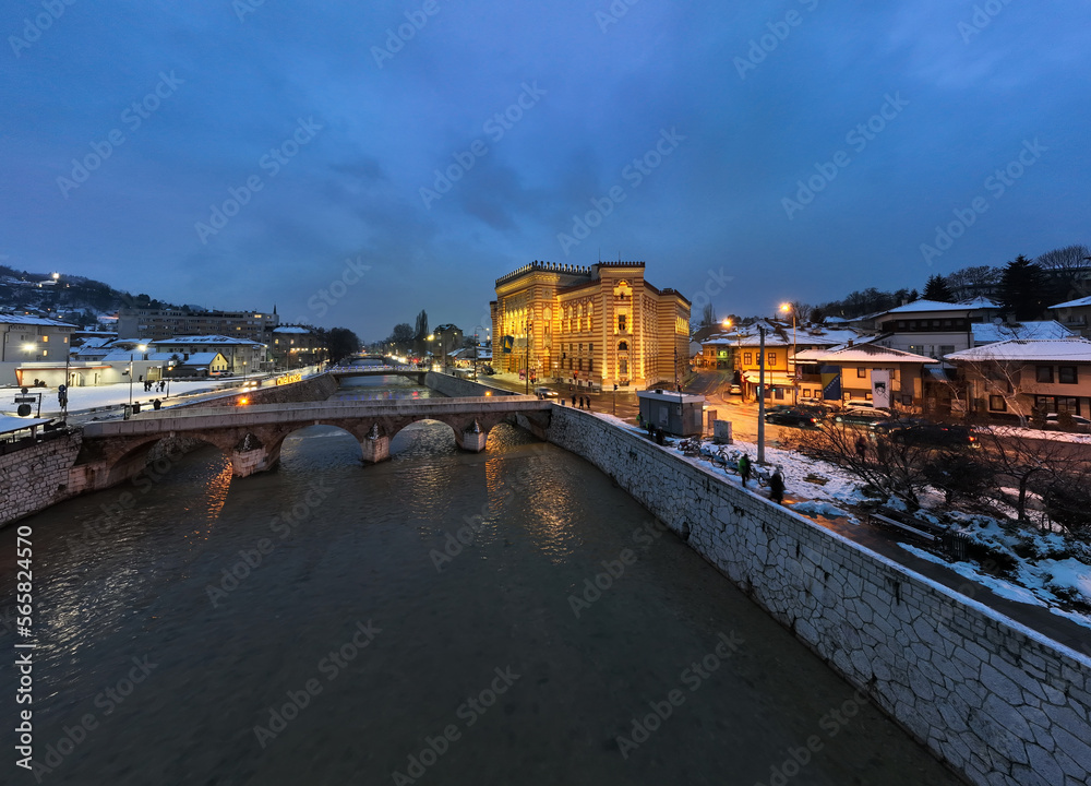 Sarajevo city hall or national library in town center aerialhyper lapse or time lapse. Landmark in capital of Bosnia and Herzegovina covered with fresh snow in the winter season at night. 