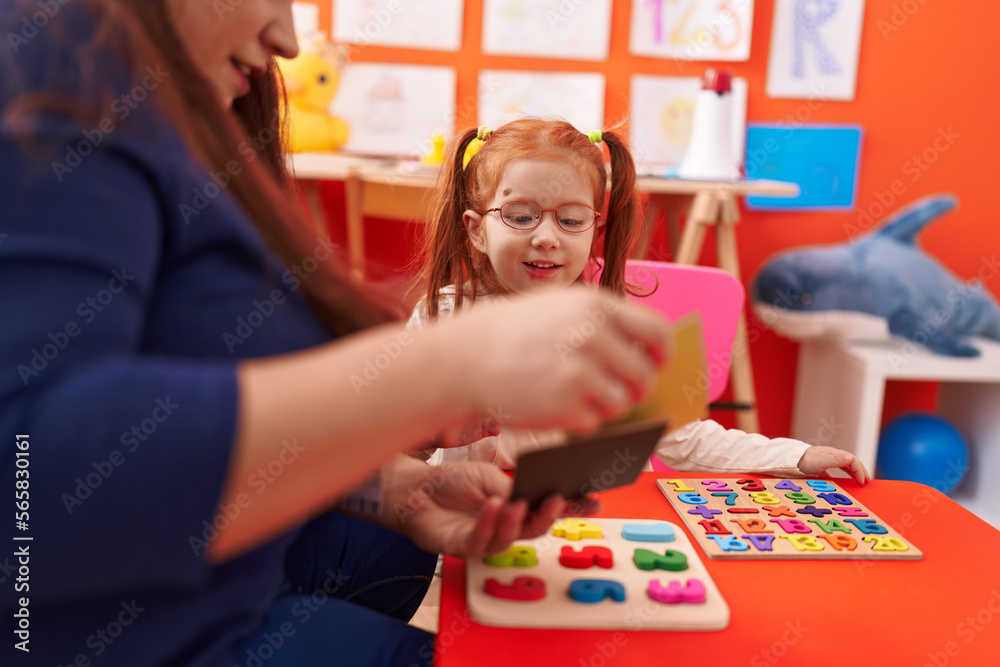 Fototapeta premium Teacher and student playing with maths puzzle game looking cards at kindergarten
