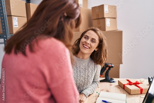 Two women ecommerce business workers smiling confident shake hands at office