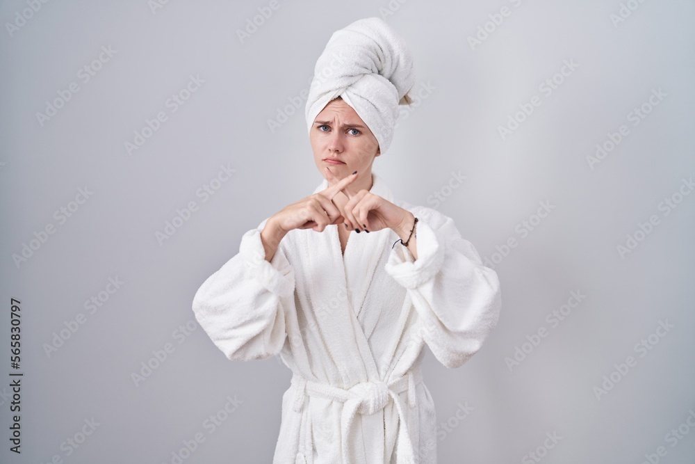 Blonde caucasian woman wearing bathrobe rejection expression crossing fingers doing negative sign Blonde caucasian woman wearing bathrobe rejection expression crossing fingers doing negative sign