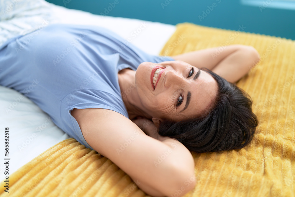Middle age hispanic woman smiling confident lying on bed at bedroom Middle age hispanic woman smiling confident lying on bed at bedroom