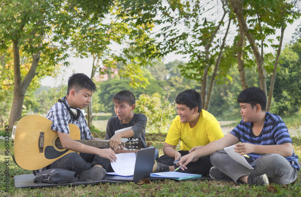 teen boy holding guitar,helping his three school junior boys to play and compose music,happy asian teenagers playing music together,concept for teenagers adult helping junior to do school arts project teen boy holding guitar,helping his three school junior boys to play and compose music,happy asian teenagers playing music together,concept for teenagers adult helping junior to do school arts project