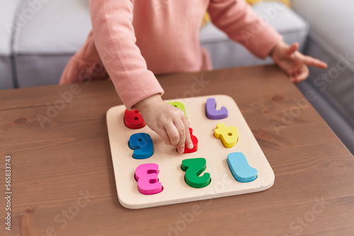 Adorable blonde girl playing maths puzzle game standing at home