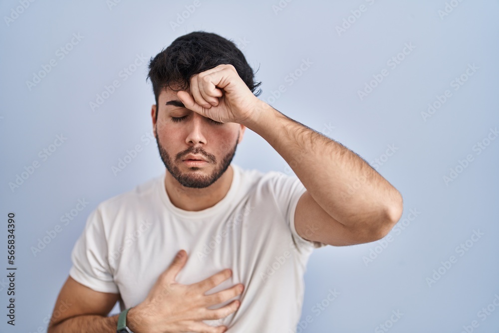Hispanic man with beard standing over white background touching forehead for illness and fever, flu and cold, virus sick Hispanic man with beard standing over white background touching forehead for illness and fever, flu and cold, virus sick