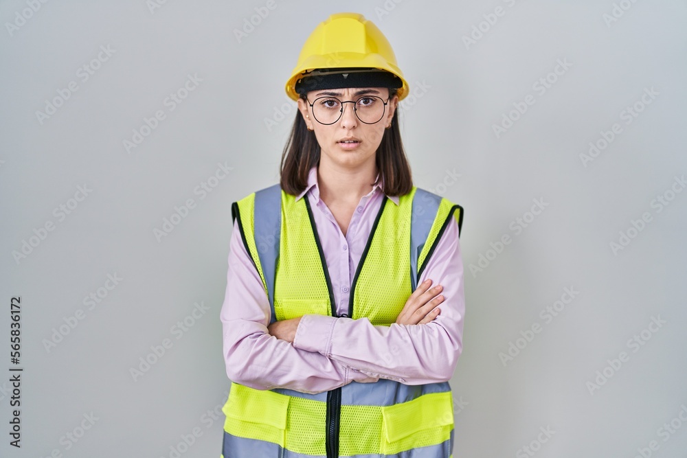 Hispanic girl wearing builder uniform and hardhat skeptic and nervous, disapproving expression on face with crossed arms. negative person. Hispanic girl wearing builder uniform and hardhat skeptic and nervous, disapproving expression on face with crossed arms. negative person.