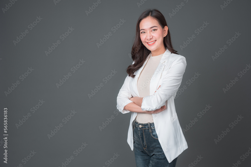 Smiling asian businesswoman standing with arms folded and looking at camera isolated over gray background. Successful 