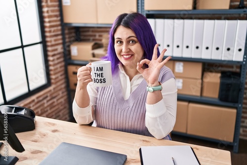 Plus size woman wit purple hair working at small business ecommerce holding i am the boss cup doing ok sign with fingers, smiling friendly gesturing excellent symbol