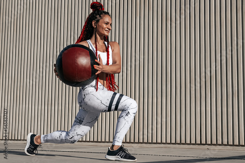 Athletic woman doing Lunge exercises with med ball. Strength and motivation.Photo of sporty woman in fashionable sportswear