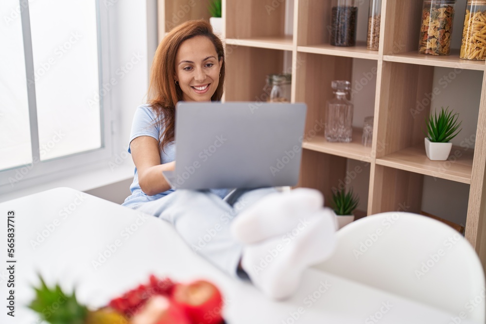 Fototapeta premium Young woman using laptop sitting on table at home