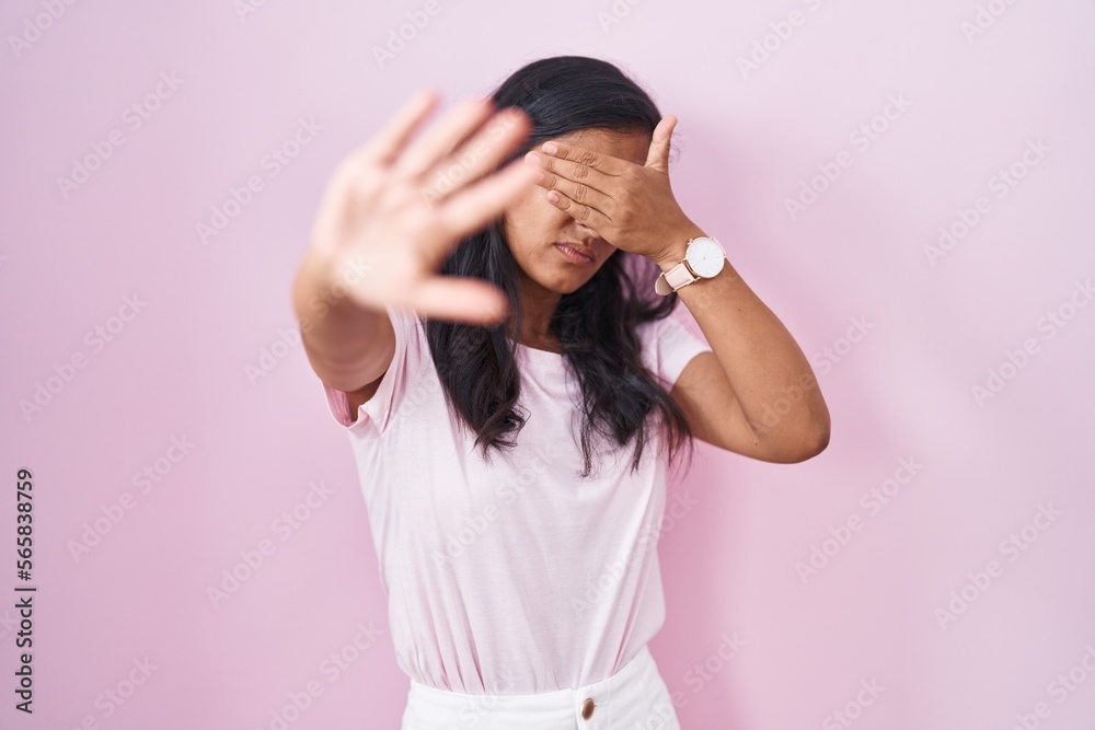 Young hispanic woman standing over pink background covering eyes with hands and doing stop gesture with sad and fear expression. embarrassed and negative concept. Young hispanic woman standing over pink background covering eyes with hands and doing stop gesture with sad and fear expression. embarrassed and negative concept.