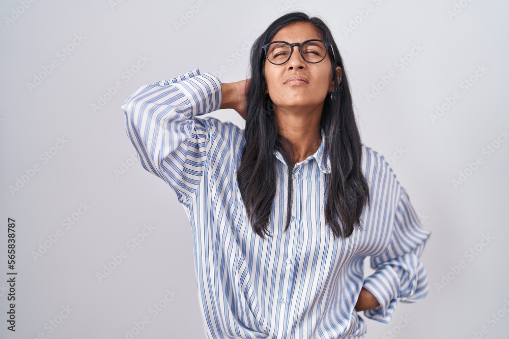 Young hispanic woman wearing glasses suffering of neck ache injury, touching neck with hand, muscular pain
