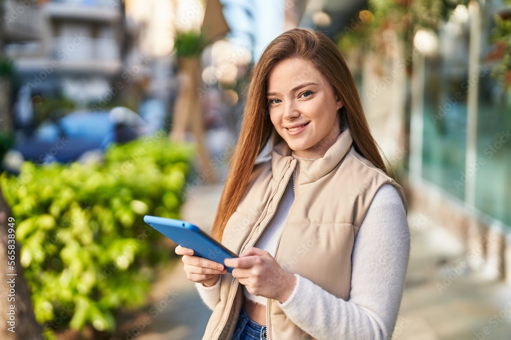 Obraz premium Young blonde woman smiling confident using touchpad at street