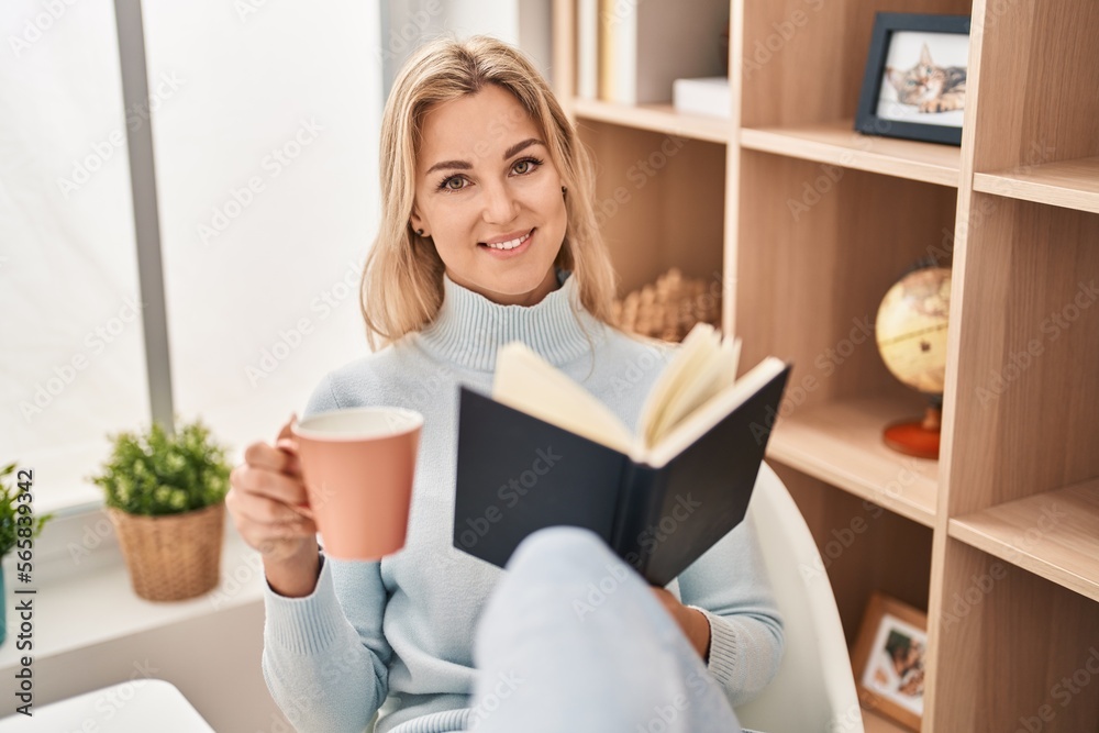 Young blonde woman reading book and drinking coffee at home Young blonde woman reading book and drinking coffee at home