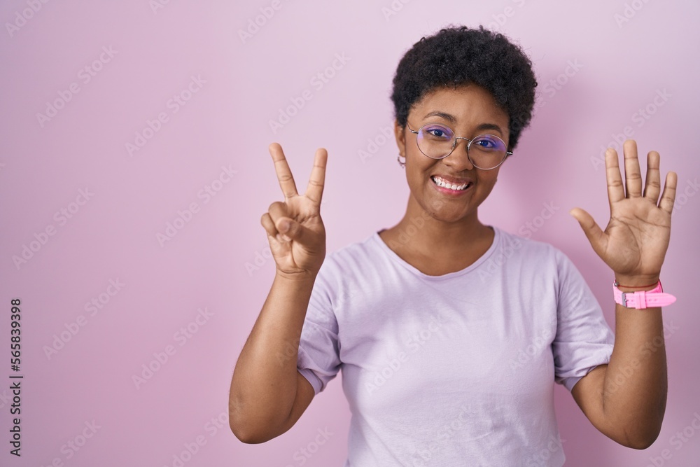 Young african american woman standing over pink background showing and pointing up with fingers number seven while smiling confident and happy. Young african american woman standing over pink background showing and pointing up with fingers number seven while smiling confident and happy.