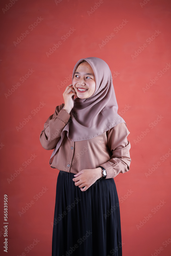 Beautiful Asian woman in brown shirt and hijab smiling cheerfully hand on chin on brown background Beautiful Asian woman in brown shirt and hijab smiling cheerfully hand on chin on brown background