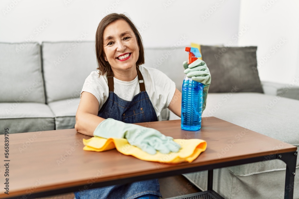 Middle age hispanic woman working as housekeeper cleaning table at home Middle age hispanic woman working as housekeeper cleaning table at home