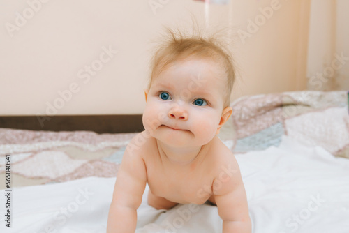 a funny baby crawling in the nursery at home. the baby is 6 months old learning to crawl