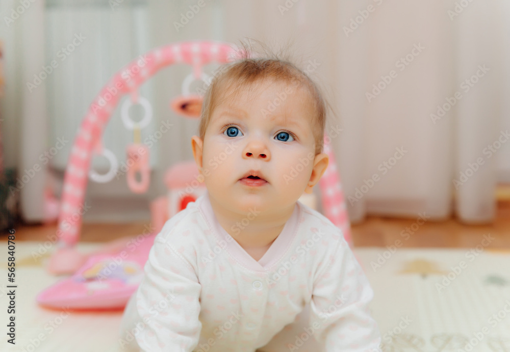 A six-month-old baby plays on the floor with colorful toys. The baby learns to crawl. portrait of a 6 month old baby A six-month-old baby plays on the floor with colorful toys. The baby learns to crawl. portrait of a 6 month old baby