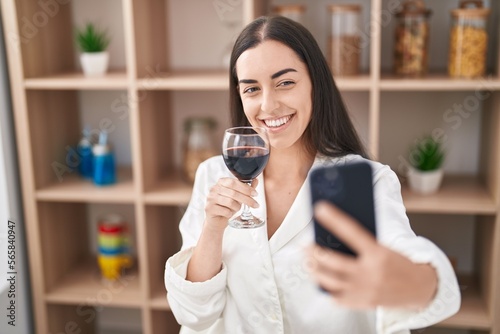 Young hispanic woman make selfie by the smartphone and drinking wine at home