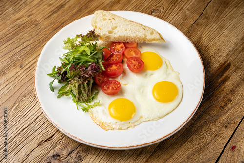 a delicious breakfast on a plate prepared in the restaurant. Fried eggs with tomatoes and salad 