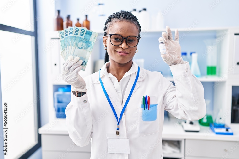 African woman with braids working at scientist laboratory holding money smiling looking to the side and staring away thinking.
