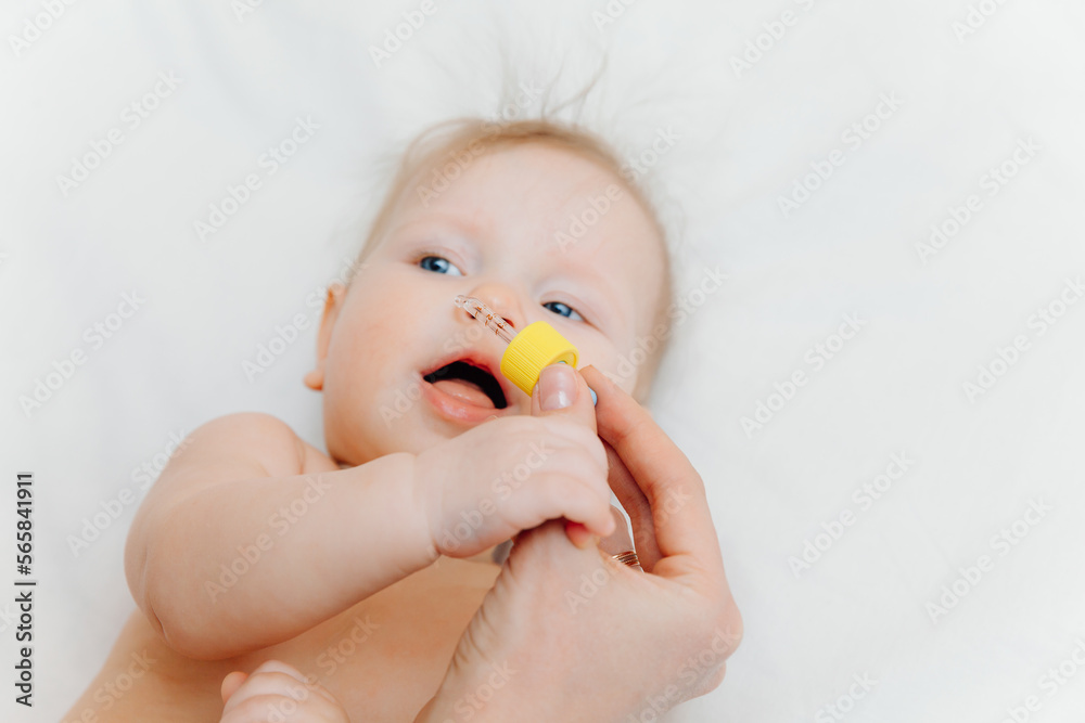 mother drips drops into the nose of the baby. sick child, the child stays in bed, mother gives him medicine and checks the temperature.