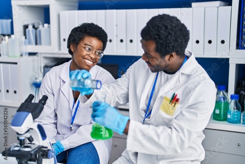 African american man and woman scientists measuring liquid at laboratory